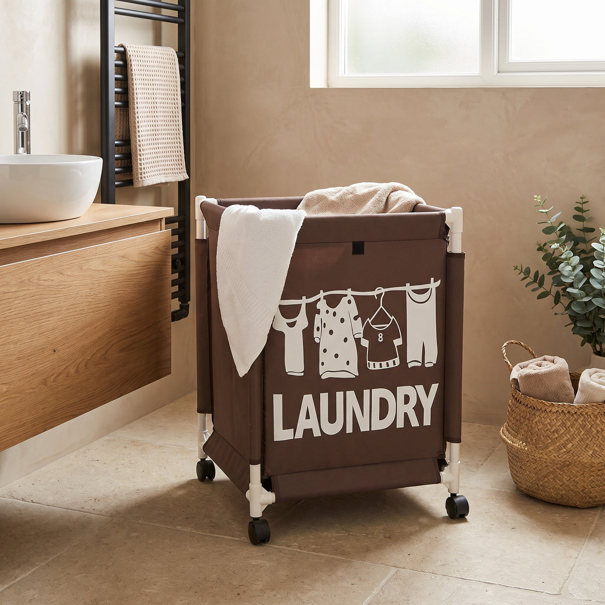 Panier à linge roulant marron en tissu Oxford dans une salle de bain, serviettes posées sur le bord