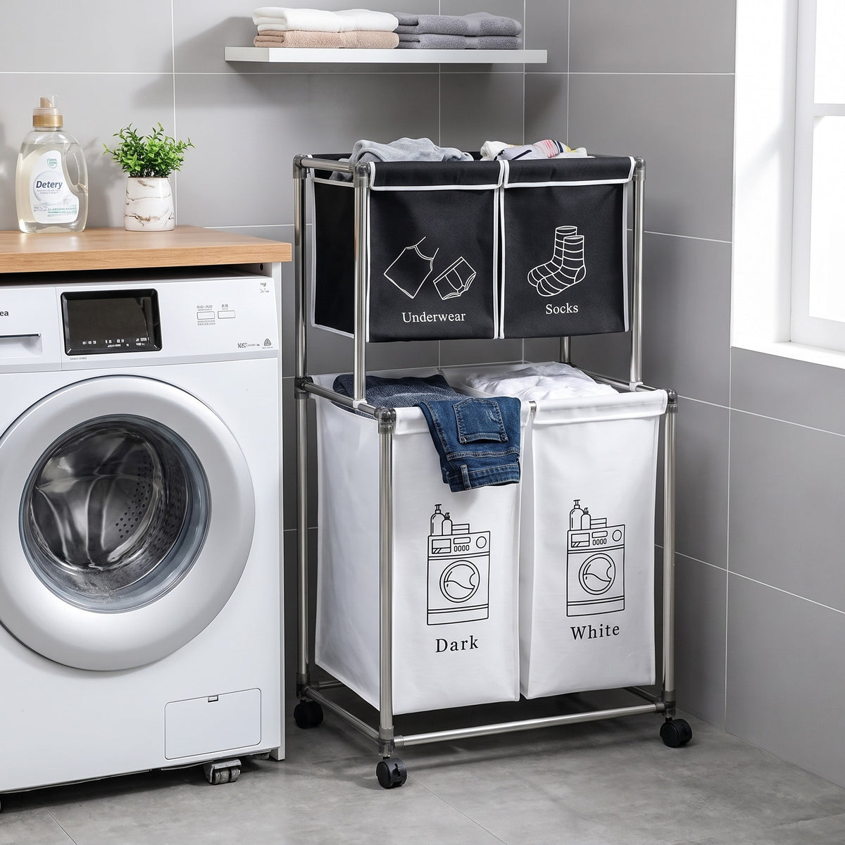 Trieur à linge 4 sacs sur roulettes placé à côté d'une machine à laver, deux sacs noirs en haut et deux sacs blancs en bas